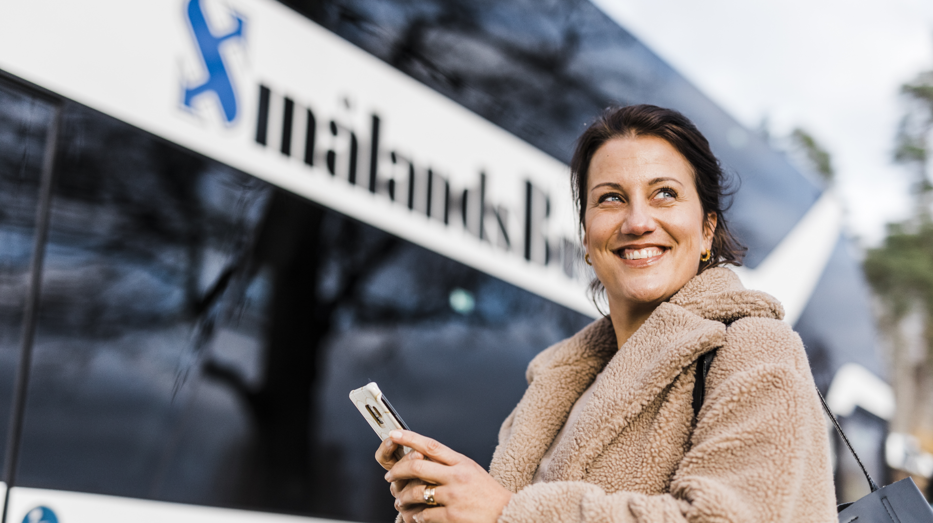 Kvinna skrattar framför Smålandsbussen